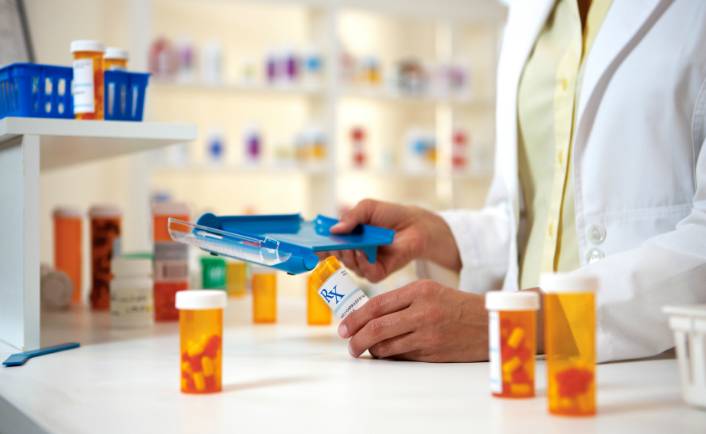 A pharmacist handling medication boxes in a pharmacy.